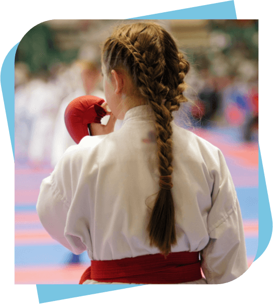 Girl with a braided ponytail at a martial arts tournament putting in a mouth guard.