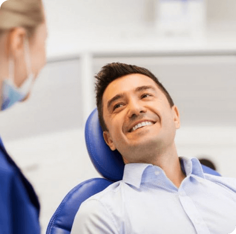 man in a dental chair smiling at his dentist