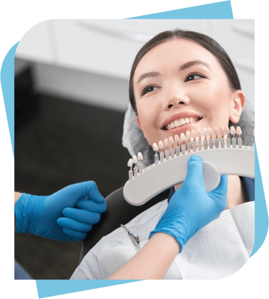 Asian woman sitting in a dental chair being show a dental crown display to match tooth colour.