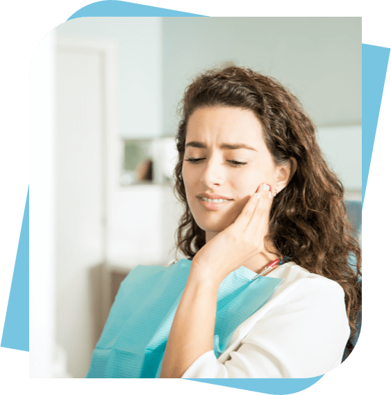 Woman in a dental chair massaging her jaw because of tooth pain.