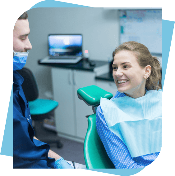 Woman sitting in a dental chair smiling while she talks with her dentist