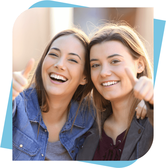 2 Young women giving a thumbs up and smiling for the camera.