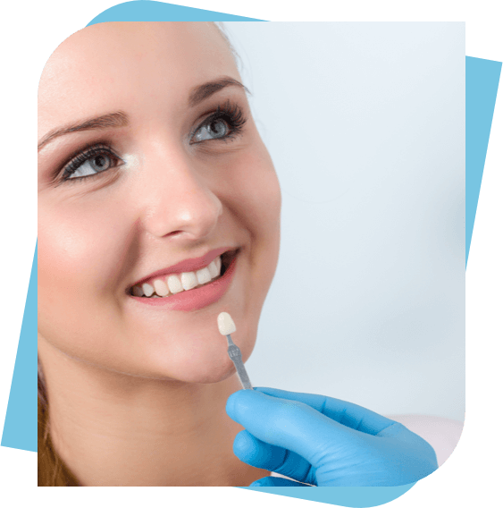 Woman Smiling while dentist holds a porcelain veneer.