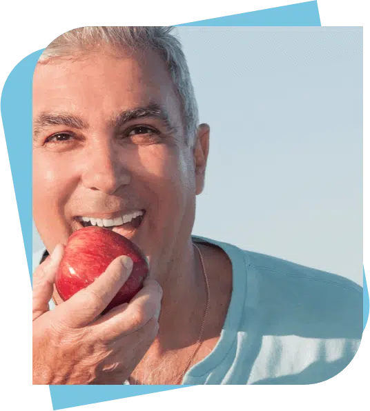 Middle aged man about to take a bite from an apple.