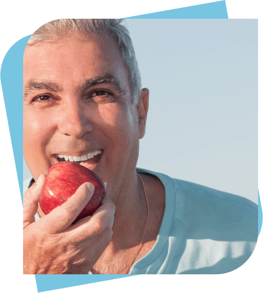 Middle aged man about to take a bite from an apple.