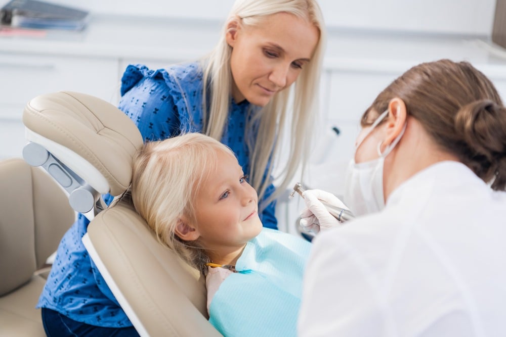 family dentist cleaning a young patients teeth