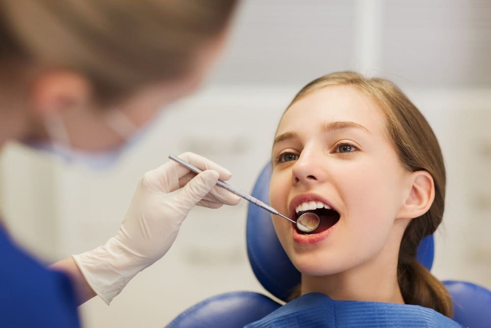 a family dentist checking the teeth of a young patient