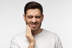 man experiencing jaw pain after tooth extraction