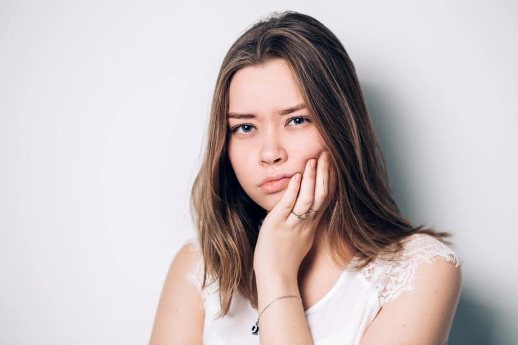 girl experiencing jaw pain after tooth extraction