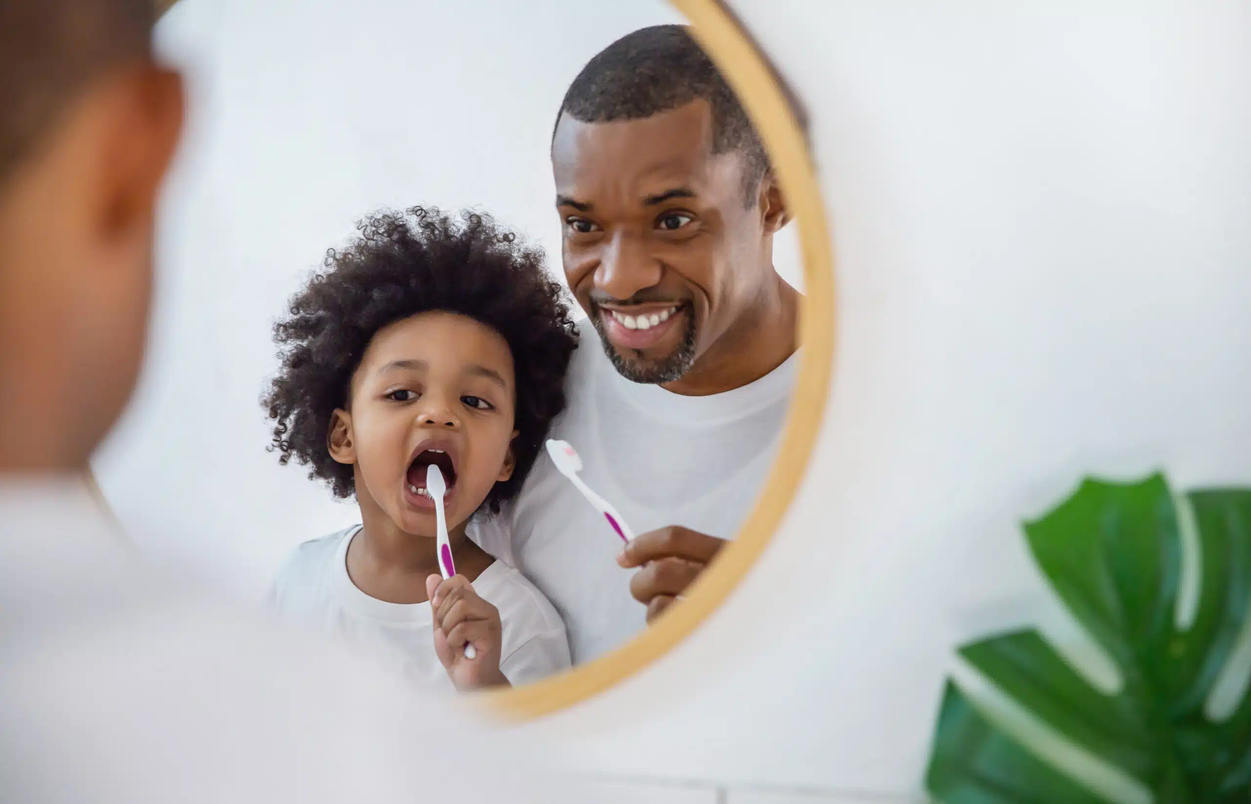 Mirror view of Father and son child brushing teeth.