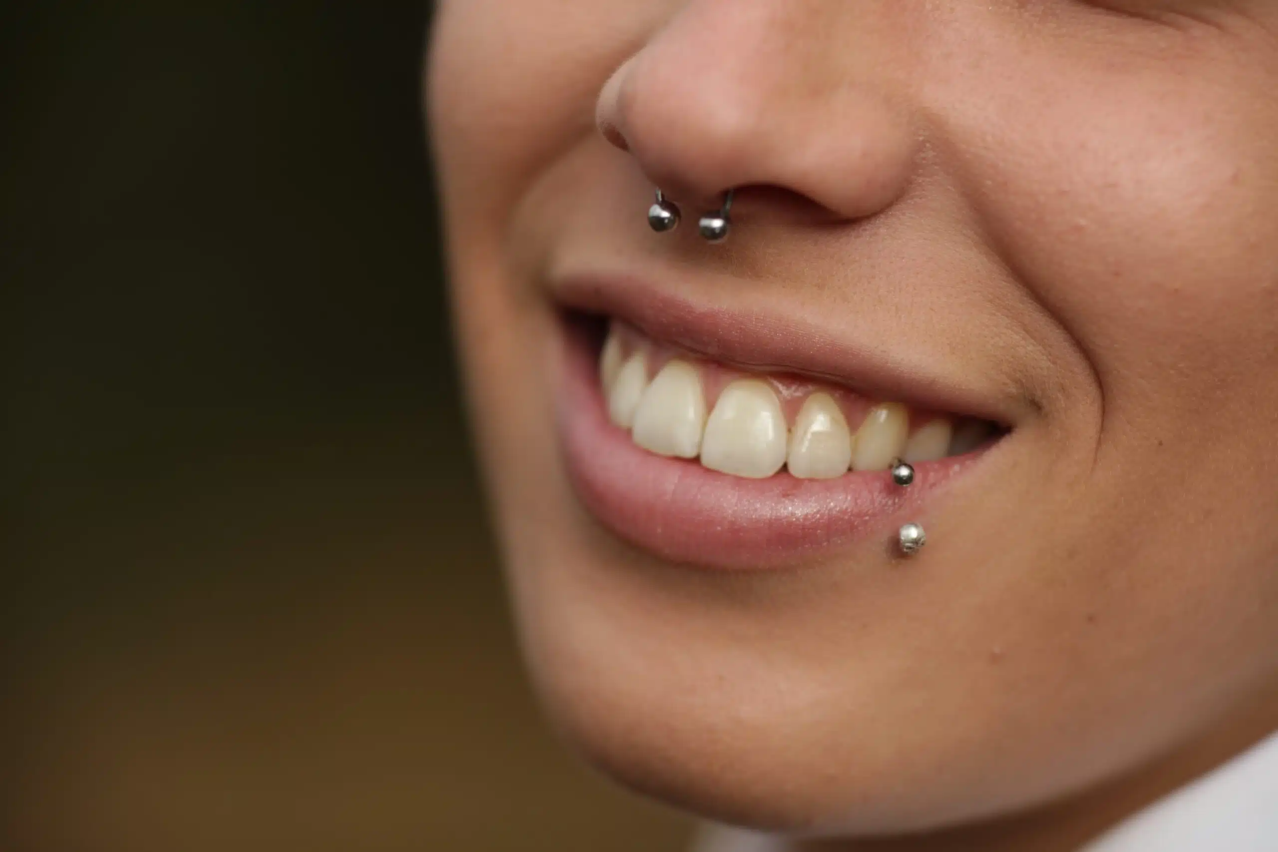 A smiling Black woman shown from the nose down with a septum piercing and lip ring.